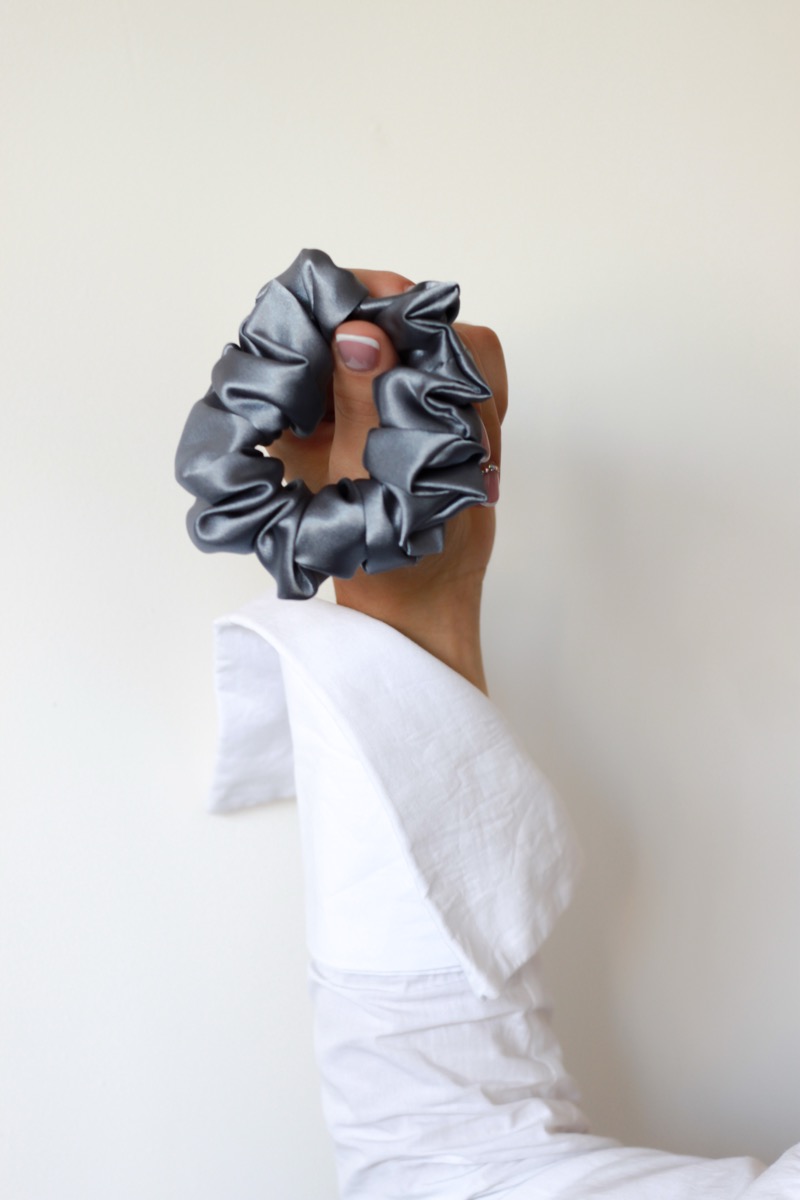 Ranka laikanti pilką šilkinę gumytę